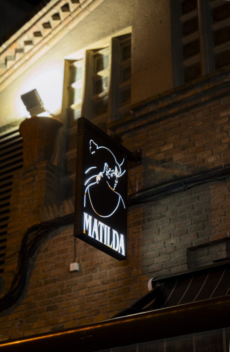 Rètol il·luminat de Matilda a la façana de maó de nit